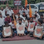 Devotees and villagers sitting on a peaceful protest at Collector Chauraha with placards supporting Baba Bhootnath Mandir, highlighting the Indore and Rangwasa location.
