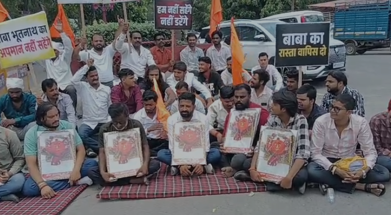 Devotees and villagers sitting on a peaceful protest at Collector Chauraha with placards supporting Baba Bhootnath Mandir, highlighting the Indore and Rangwasa location.
